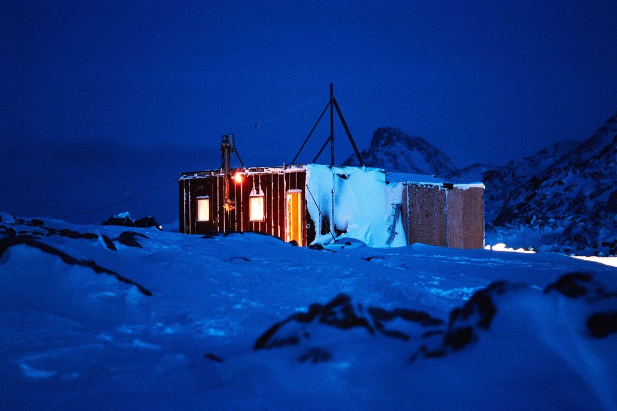Beleuchtete Unterkunft in nächtlicher Schneelandschaft
