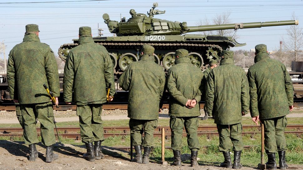 Während um einen Abzug von der Grenze zur Ostukraine gerungen wird, verstärkt Russland seine Positionen auf der Krim: Russische Soldaten beobachten, wie aufgerüstete T-72-Panzer in Gwardejskoe in der Nähe der Hauptstadt der Krim, Simferopol, von einem Zug abgeladen werden. (31. März 2014)