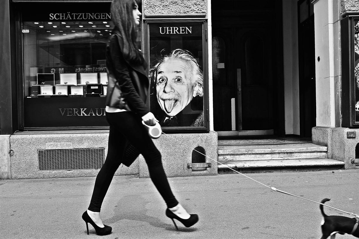 Frau spaziert mit Hund an Einstein-Plakat vorbei