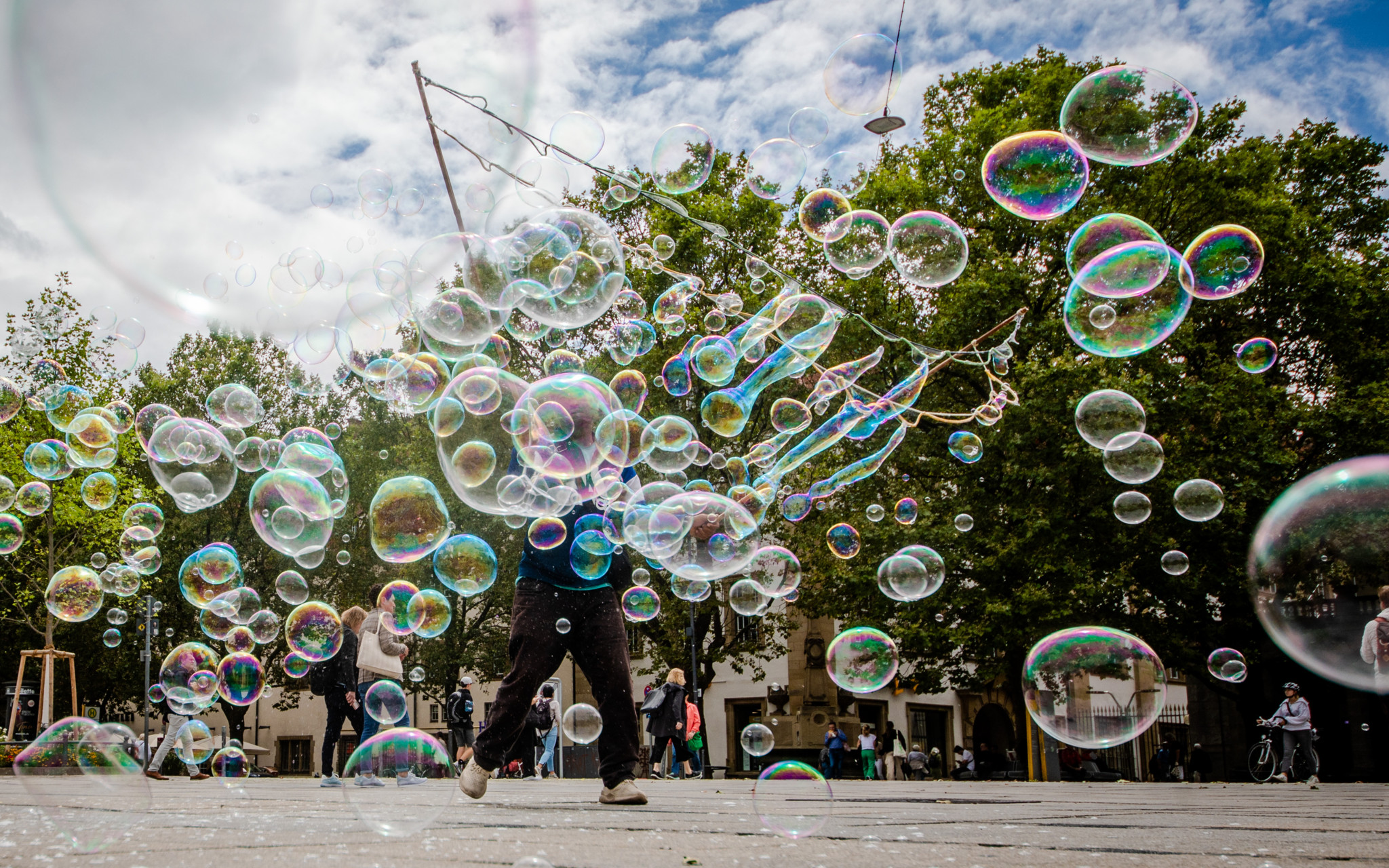 03.08.2023, Baden-Württemberg, Stuttgart: Bei einem Mix aus Sonne und Wolken produziert ein Mann in der Stuttgarter Innenstadt Seifenblasen für vorbeilaufende Passanten. Foto: Christoph Schmidt/dpa +++ dpa-Bildfunk +++ (KEYSTONE/DPA/Christoph Schmidt)