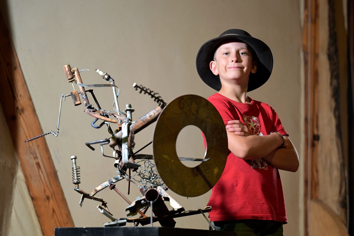 Fenalet sur Bex, le 26 juin 2024. Zak, 9 ans, présente sa première exposition de sculptures mécaniques, Les Métallogones, chez lui à Fenalet. Il pose ici avec son oeuvre, la démantibuleuse. 24HEURES/Chantal Dervey