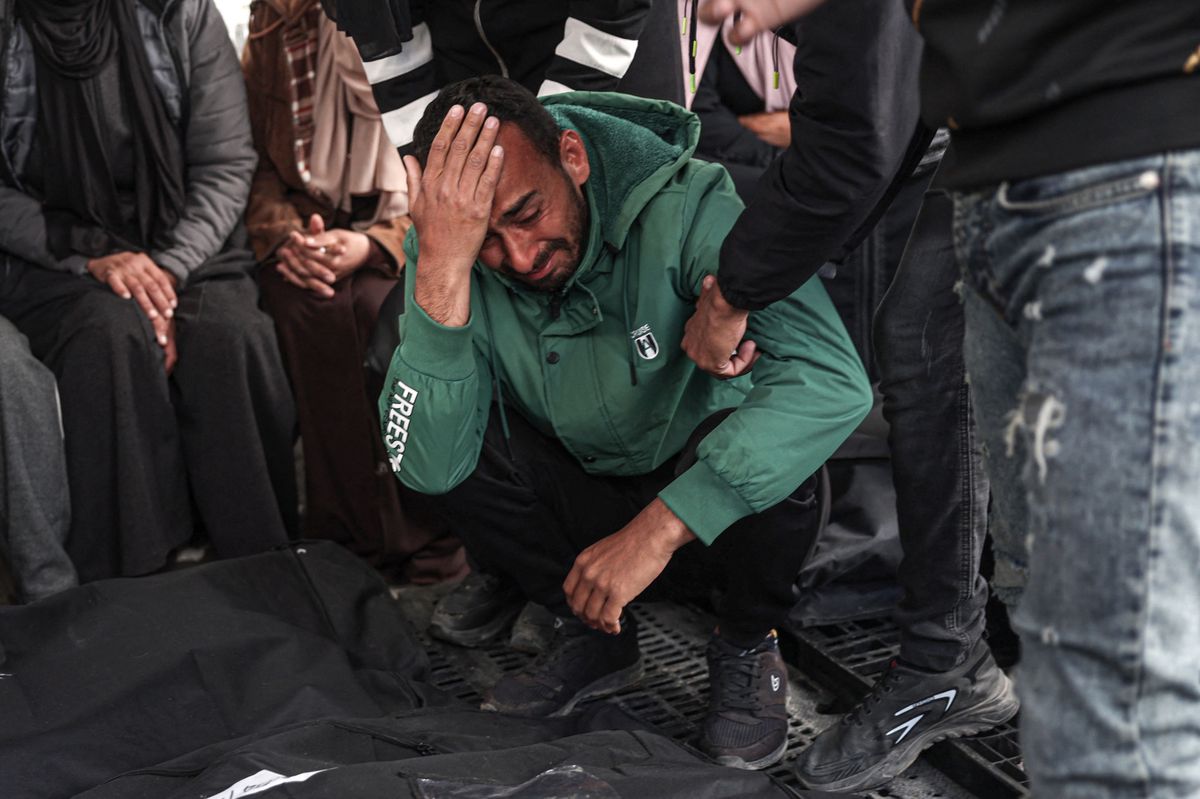 Palestinians mourn over the covered bodies of relatives, killed in overnight Israeli bombardment, at the al-Najjar hospital in Rafah in the southern Gaza Strip on March 25, 2024, amid the ongoing conflict between Israel and the militant group Hamas. (Photo by SAID KHATIB / AFP)