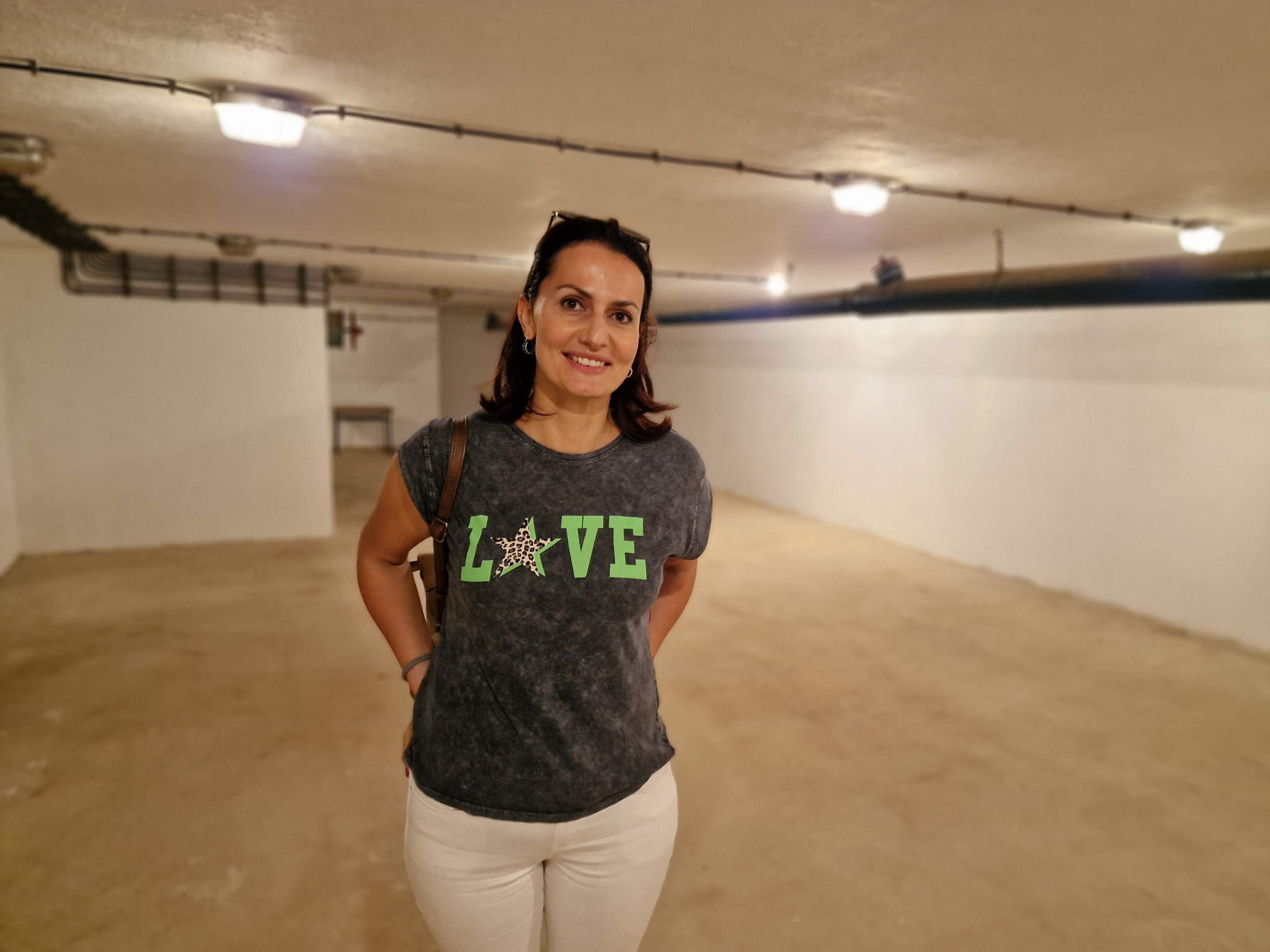 Frau in einem weissen Raum mit Betonboden, trägt ein T-Shirt mit der Aufschrift ’LOVE’.