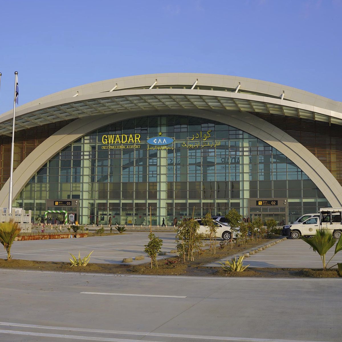 Sicherheitskräfte vor dem neu erbauten Flughafen Gwadar in Pakistan, aufgenommen am 10. Januar 2025. Mehrere Autos sind vor dem modernen Gebäude mit gewölbter Architektur zu sehen. Vor dem Gebäude wehen Fahnen in der Brise.