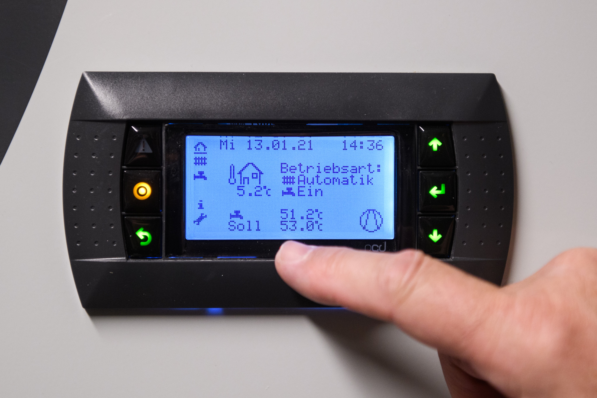 Eine Hand zeigt auf das Display einer Wärmepumpe mit den Einstellungen: Betriebsart Automatik, aktuelle Temperatur 5,2°C, Zieltemperatur 53,0°C, aufgenommen am 13.01.2021 in Laupen.