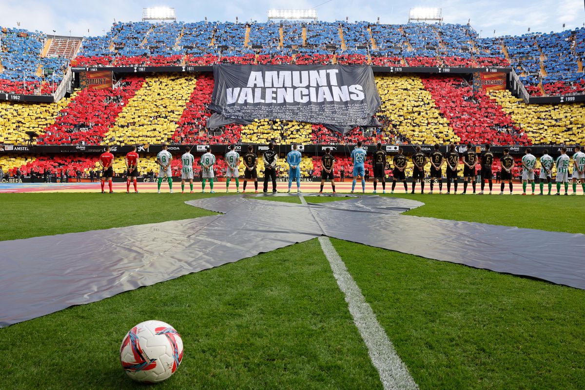 epa11736343 Players of Valencia CF and Real Betis and attendants observe one minute silence for victims of floods shortly before their LaLiga game at Mestalla Stadium, in Valencia, eastern Spain, 23 November 2024. The banner reads 'Bear Up Valencia's People'.  EPA/Ana Escobar