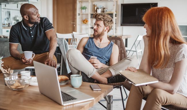 Drei Menschen sitzen an einem Tisch.