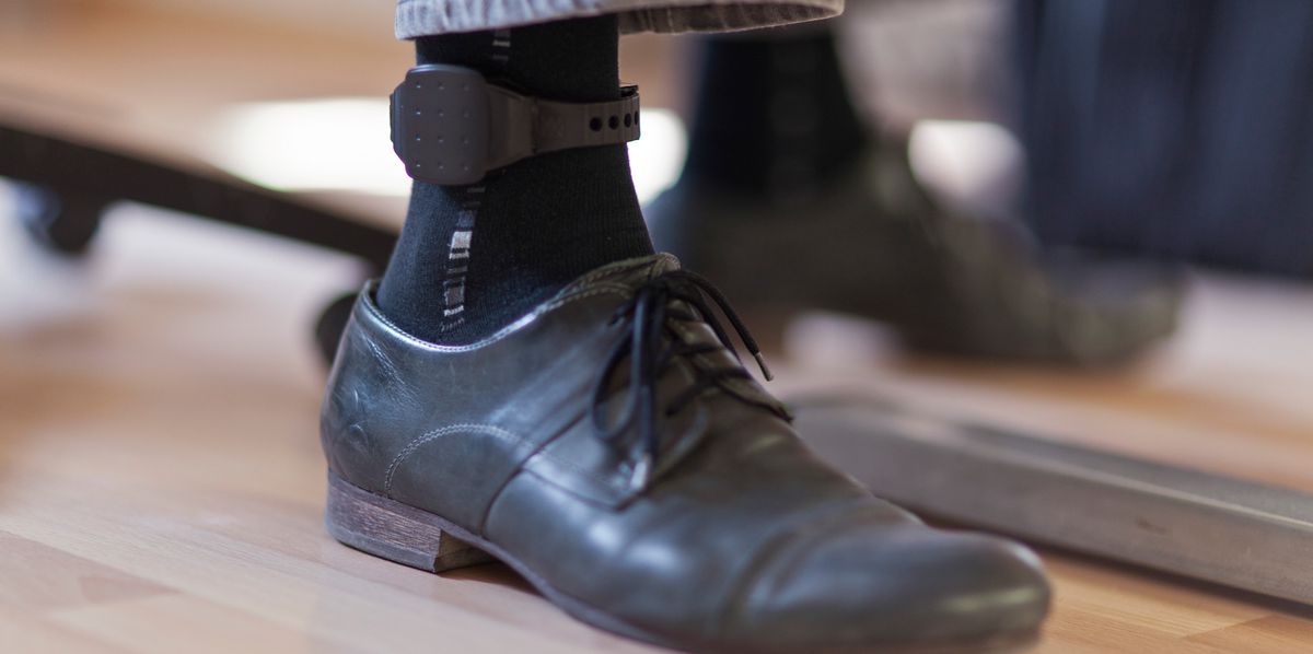 Un homme portant un bracelet électronique à la cheville travaille dans un bureau.