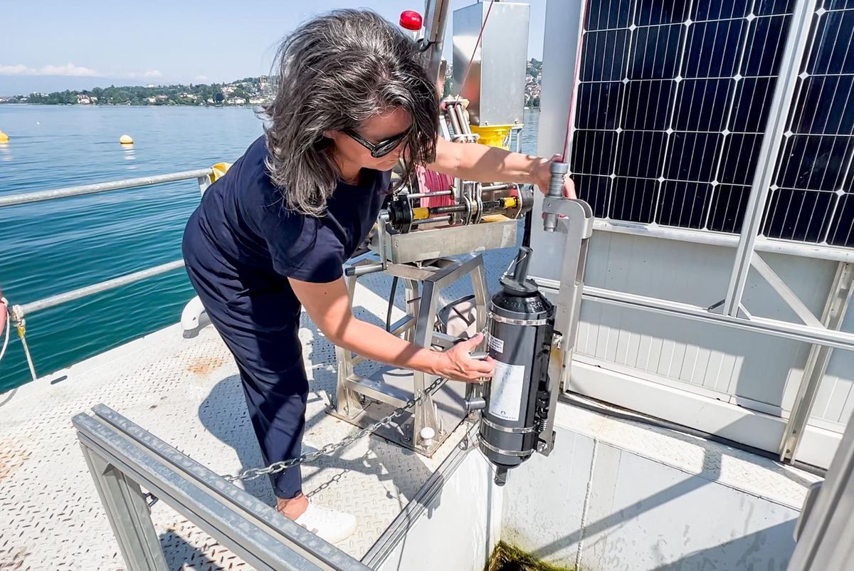La chercheuse Marie-Élodie Perga tient un appareil de mesure à bord de la plateforme LéXPLORE, sur le Léman.