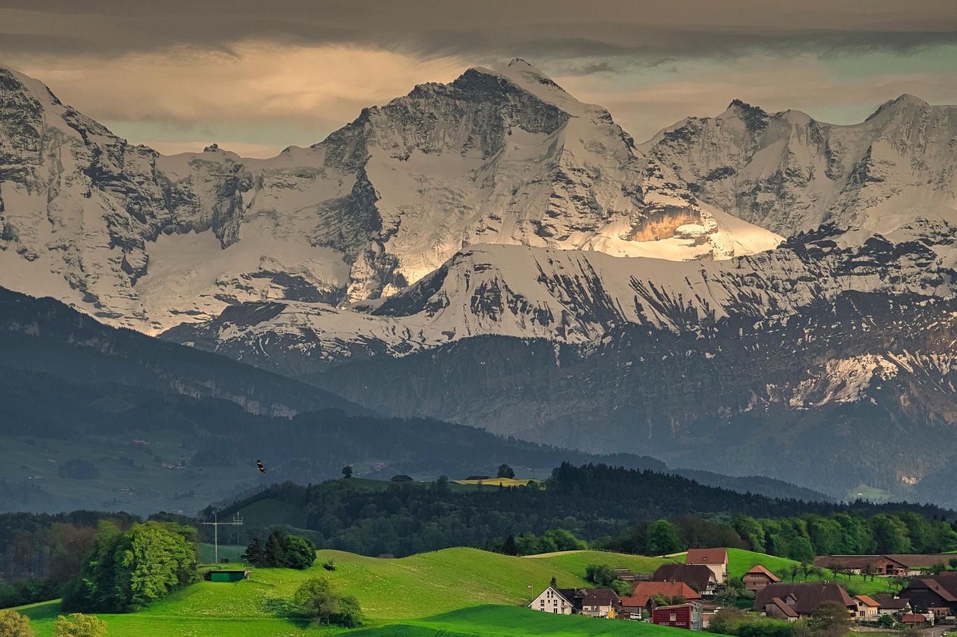 Paysage panoramique des Alpes bernoises avec un tracteur travaillant les champs agricoles sur la colline du Gurten près de Berne, Suisse.