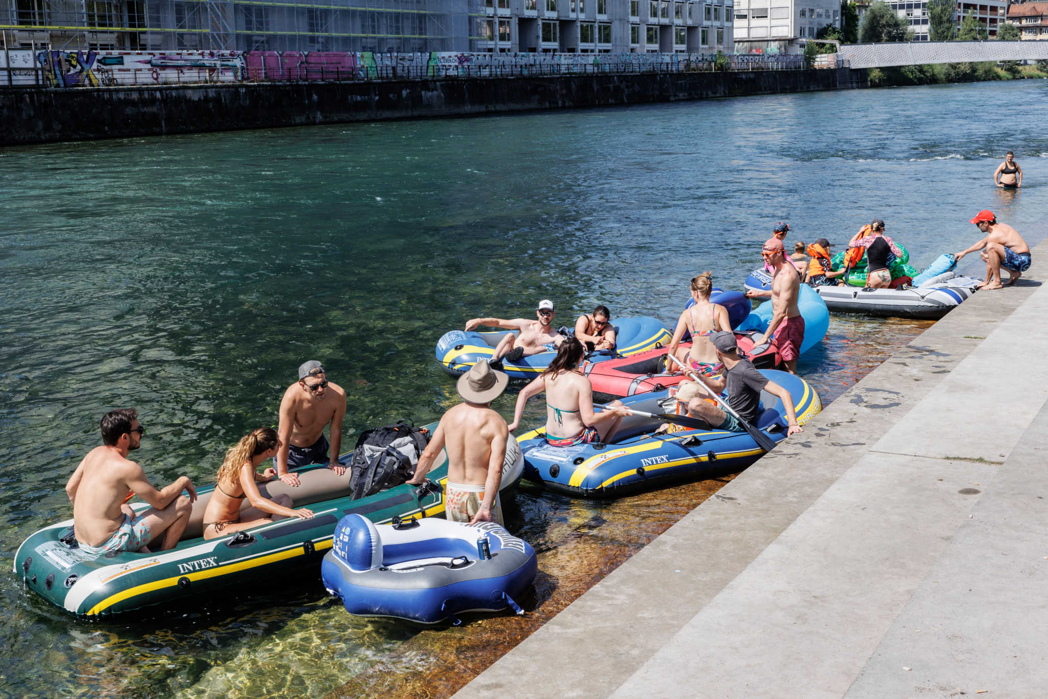 Menschen entspannen in Gummibooten auf der Limmat beim GZ Wipkingen in Zürich, sommerlicher Tag mit klarer Sicht.