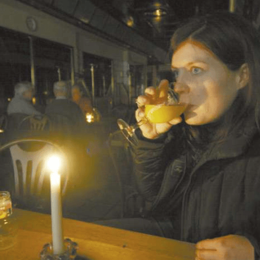 Femme buvant dans un verre dans un café faiblement éclairé par des bougies.