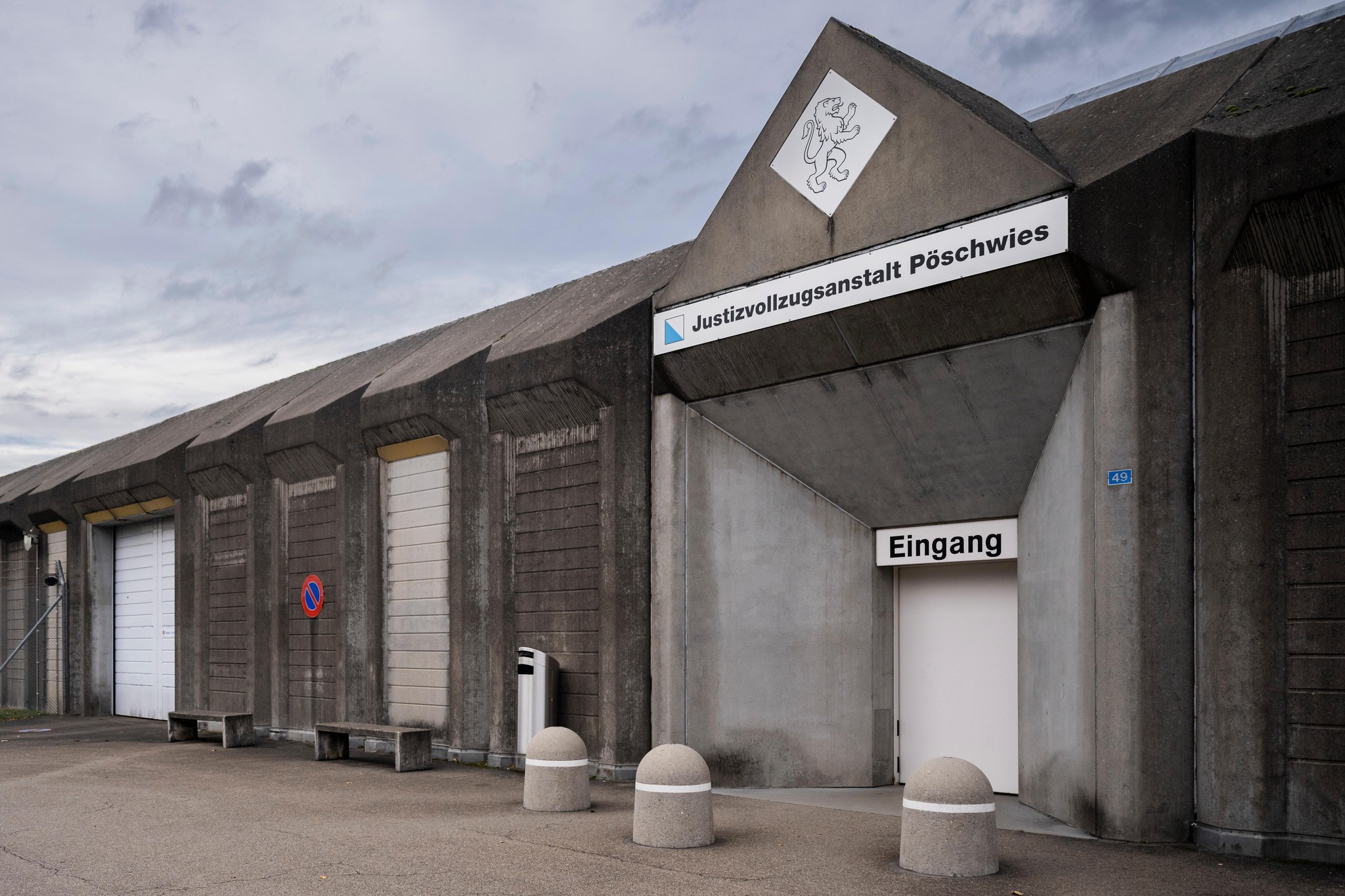 Eingang der Justizvollzugsanstalt Pöschwies mit Schild und Betonarchitektur.