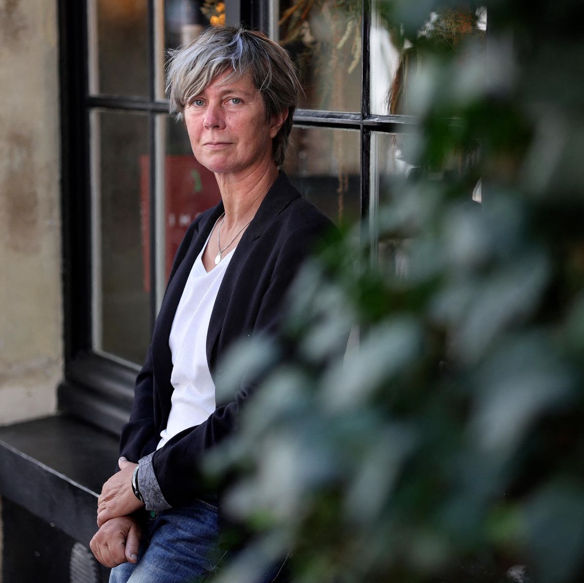 L’écrivain française Sandrine Collette pose assise devant une fenêtre à Paris, le 29 juin 2022.