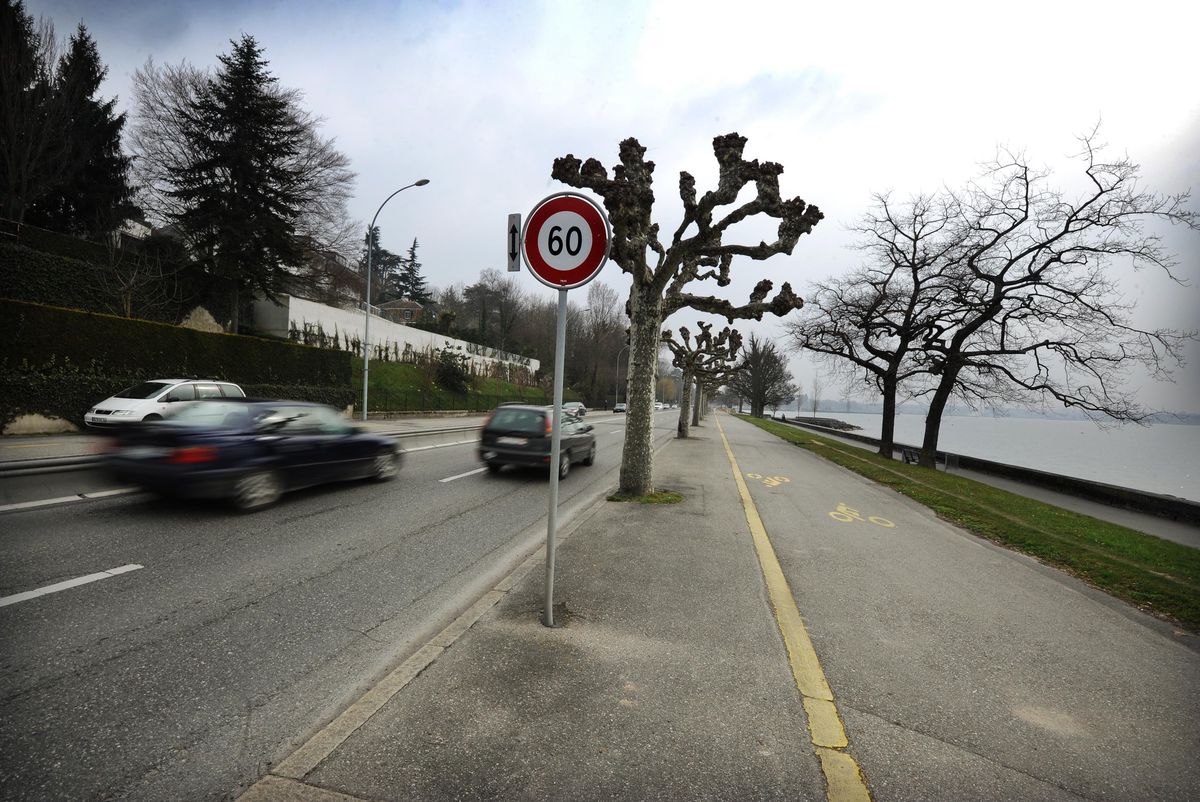 Quai de Cologny à Genève avec un panneau de limitation de vitesse à 60 km/h, des voitures en mouvement flou.