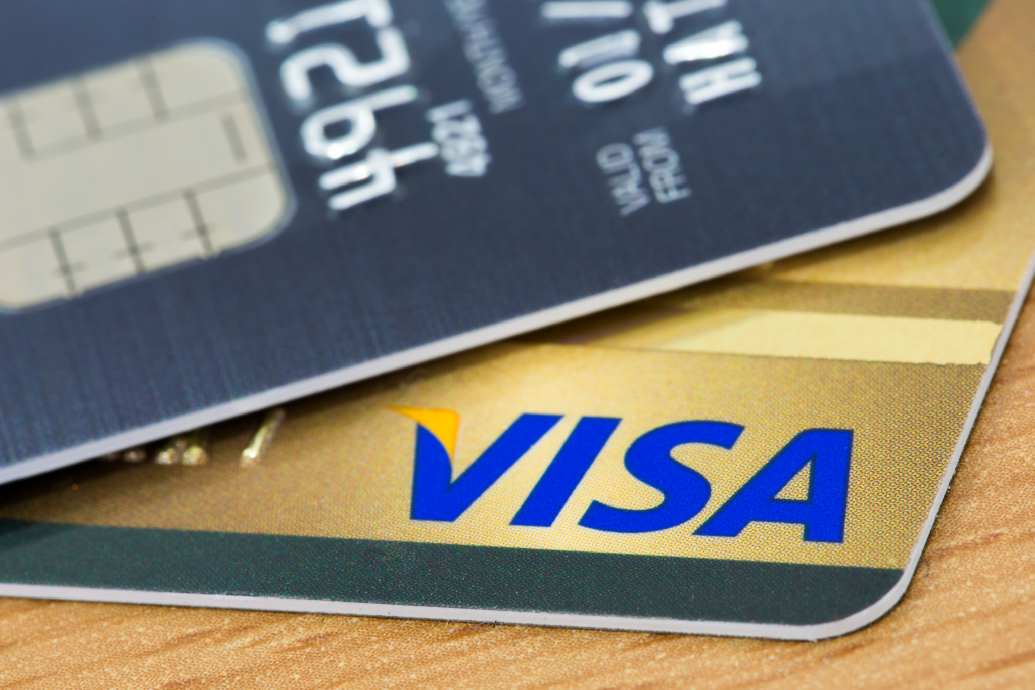 Gros plan sur une carte de crédit VISA avec puce, textures de bois en arrière-plan.