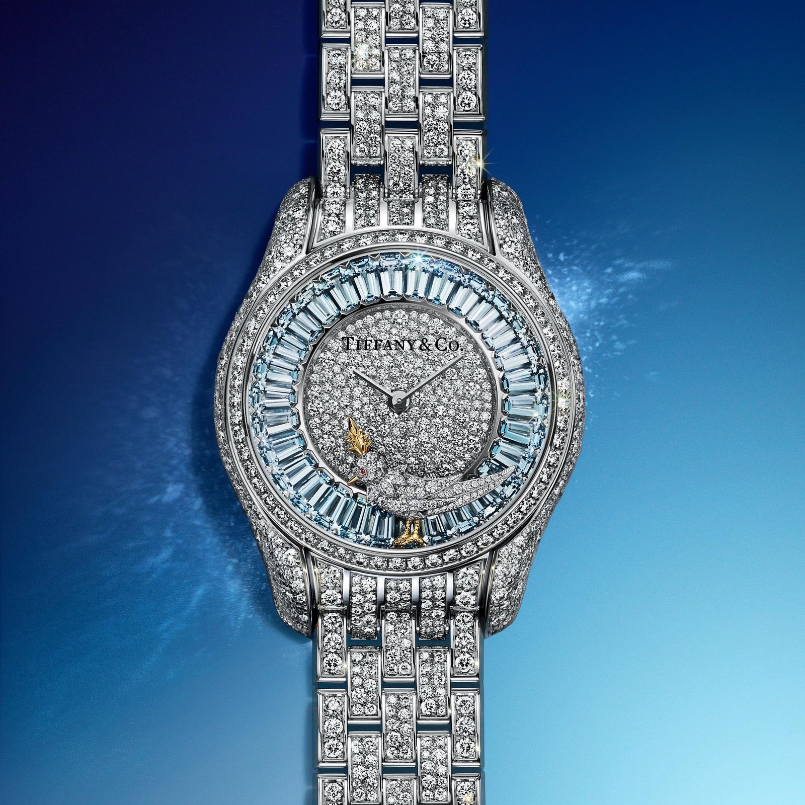 Montre en or blanc incrustée de diamants et saphirs, bracelet en métal poli, cadran étincelant sur fond bleu dégagé.