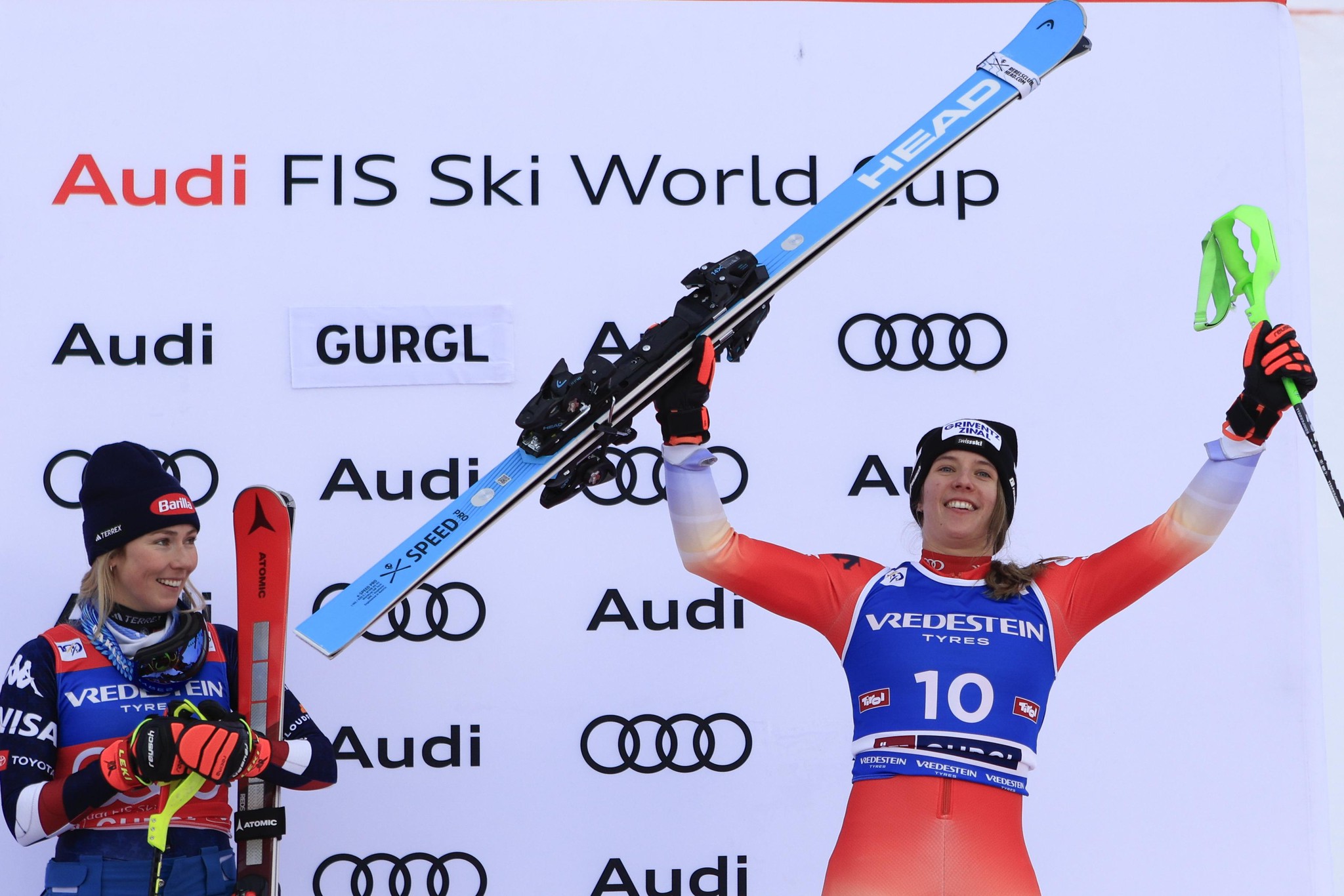 Mikaela Shiffrin und Camille Rast bei der Siegerehrung des FIS Ski Weltcups im Slalom in Gurgl, Österreich. Shiffrin hält Skier, während Rast jubelt.