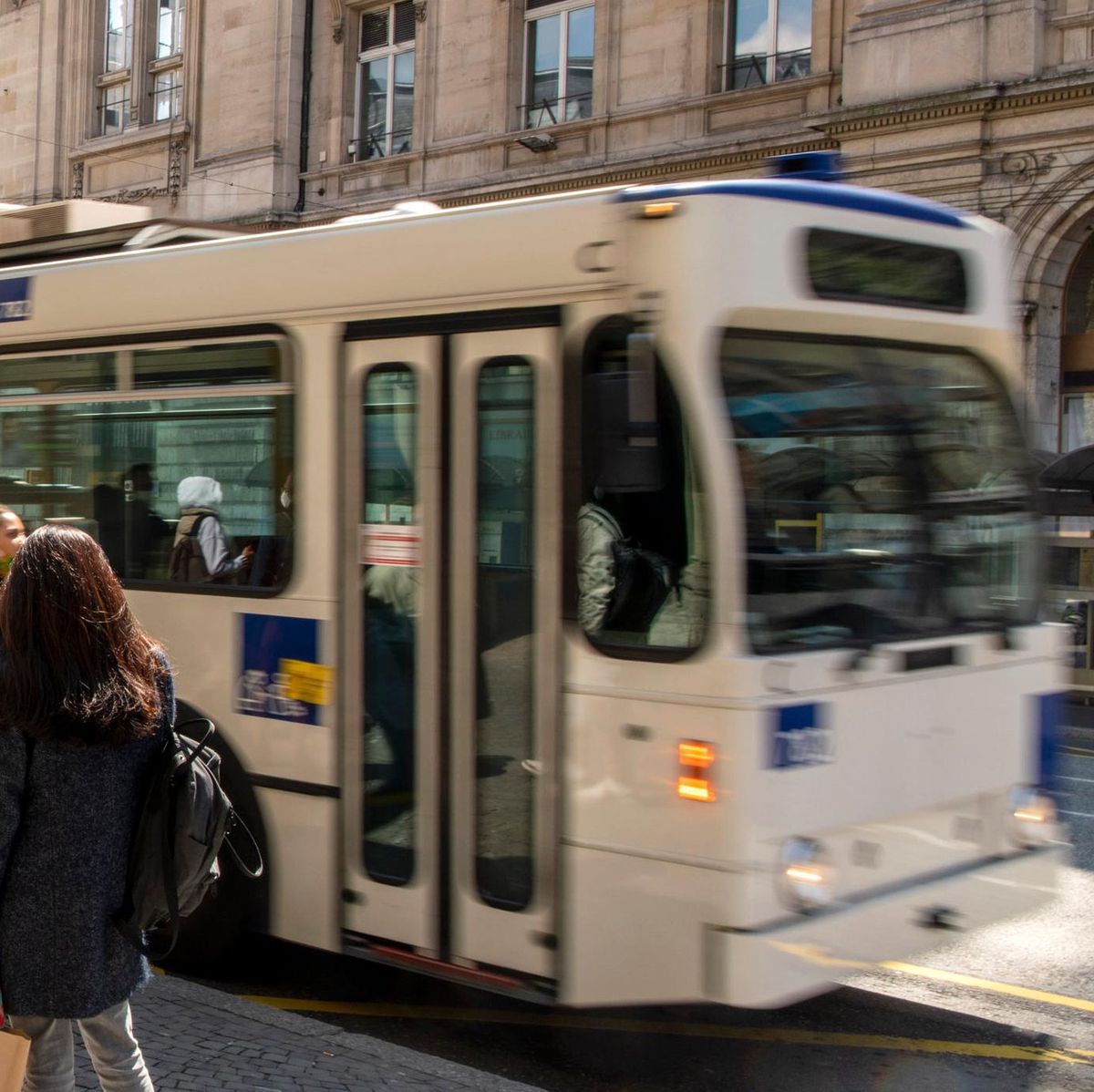 Bus des transports publics lausannois sur la place St-François à Lausanne, avec des passants près d'une machine à billets.