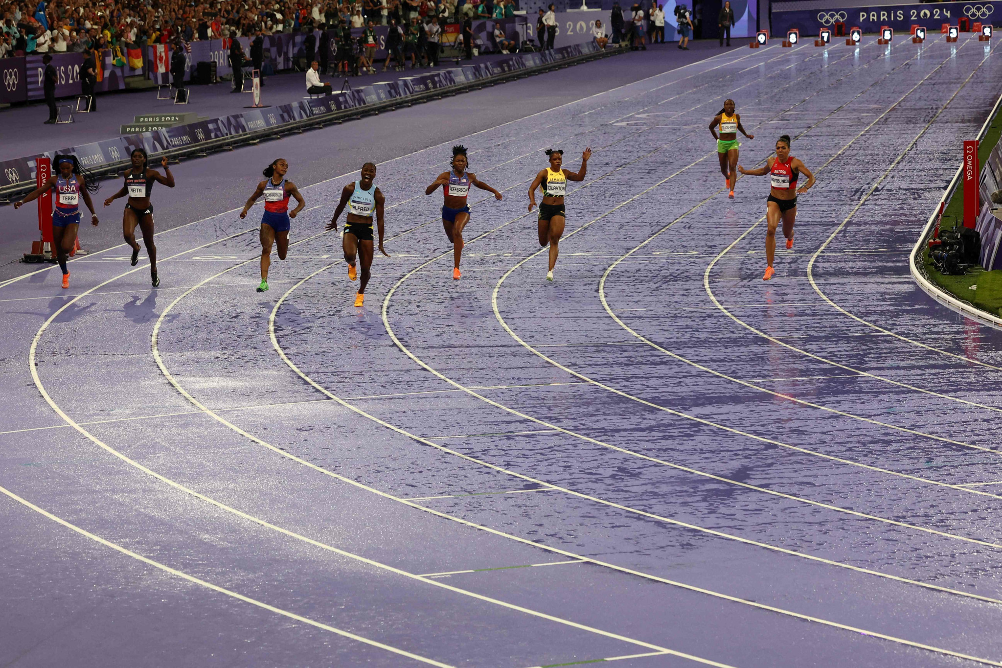 Saint Lucia's Julien Alfred celebrates after winning ahead of ahead of US' Twanisha Terry, Britain's Daryll Neita, US' Sha'carri Richardson, US' Melissa Jefferson, Jamaica's Tia Clayton, Ivory Coast's Marie-Josee Ta Lou and Switzerland's Mujinga Kambundji in the women's 100m final of the athletics event at the Paris 2024 Olympic Games at Stade de France in Saint-Denis, north of Paris, on August 3, 2024. (Photo by Anne-Christine POUJOULAT / AFP)