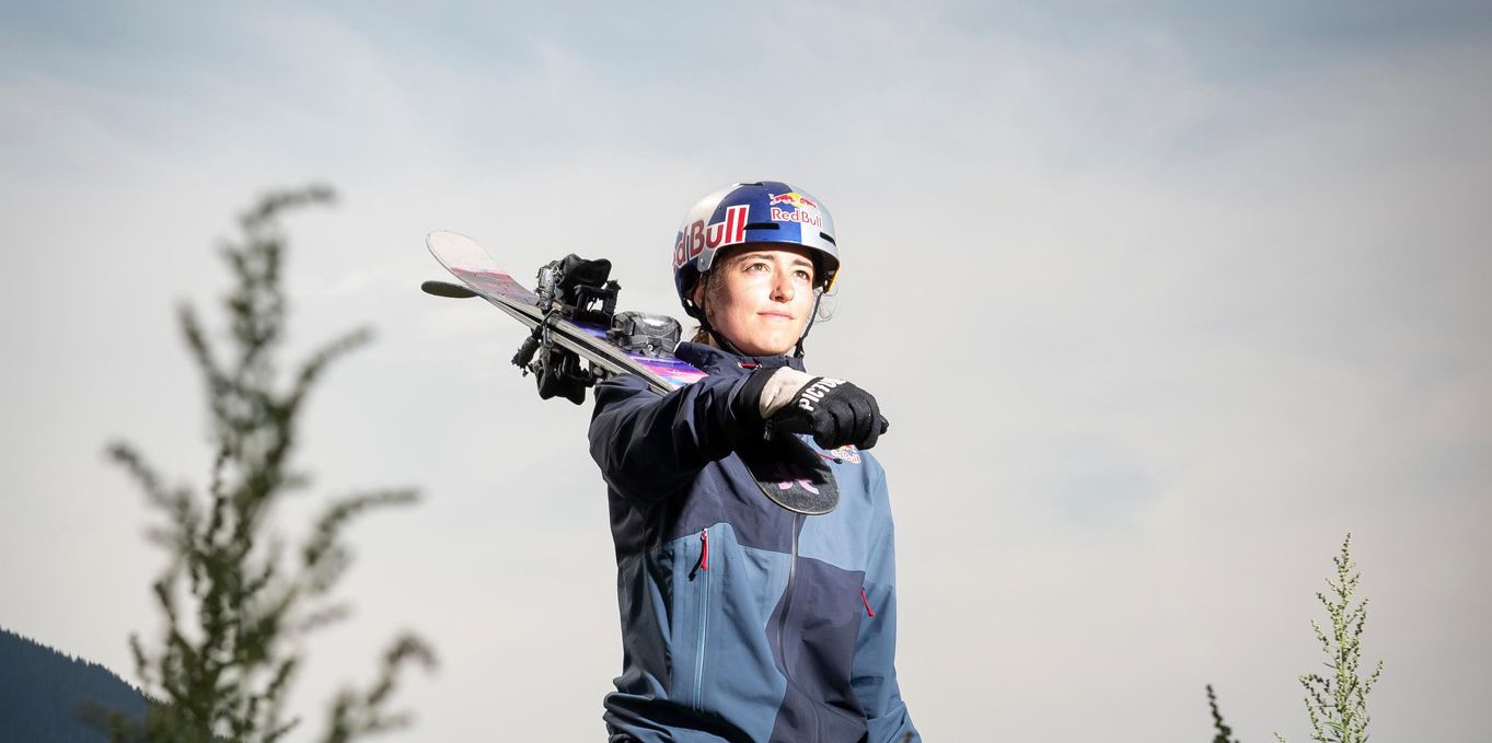 Mathilde Gremaud, membre de l'équipe de Suisse de ski freestyle, s'entraîne à Leysin sur un airbag, portant un casque et des skis, entourée de verdure. Photo: Sébastien Anex