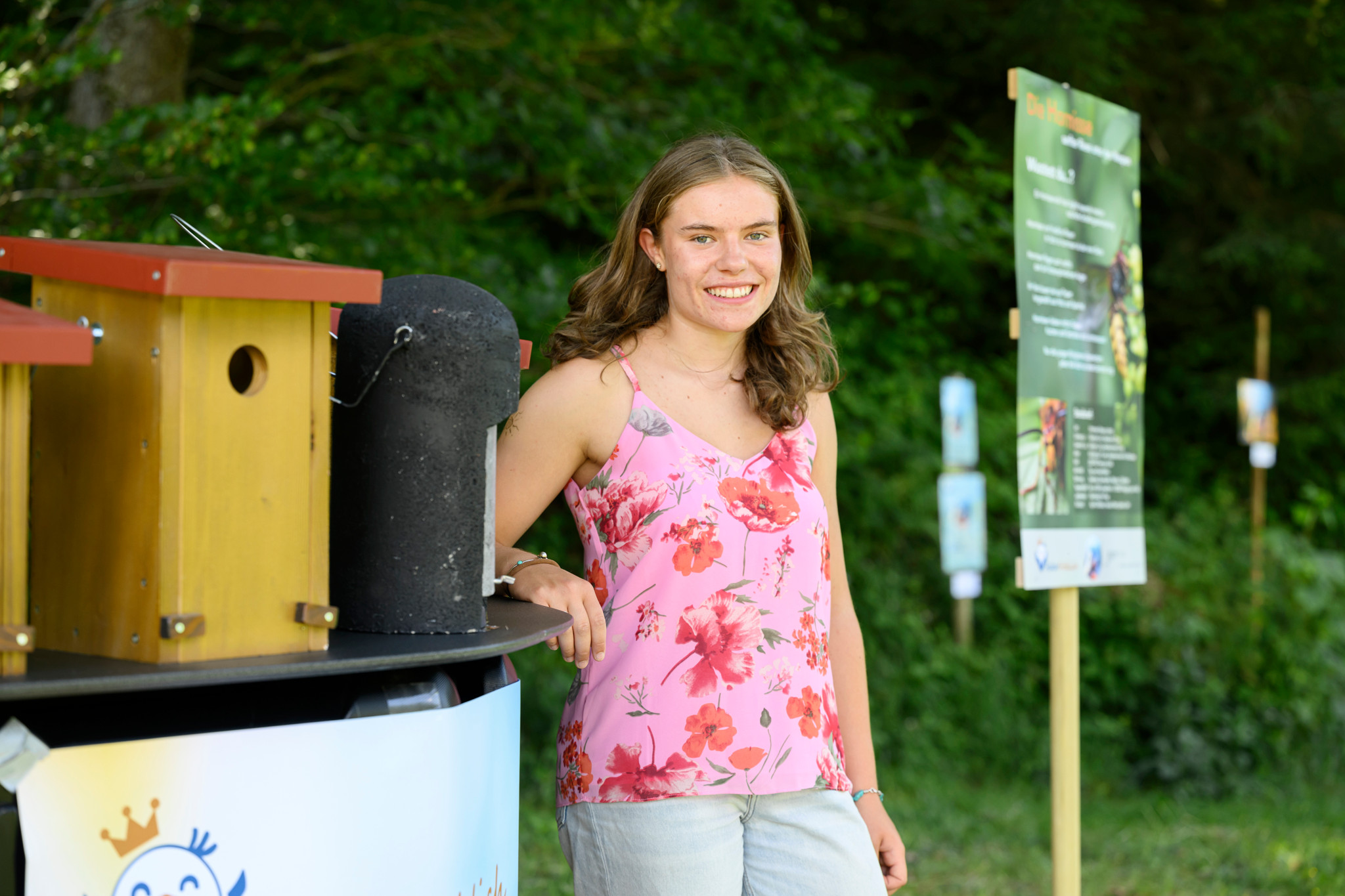 Gymnasiastin Aisla Spichiger steht lächelnd neben einem Vogelhäuschen auf dem Natur-Erlebnispfad FederFröhlich in Steffisburg.