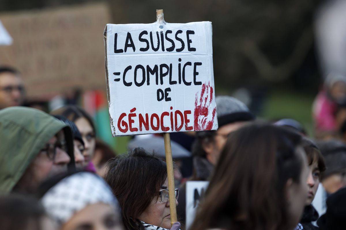 A protester holding a placard reading "La Suisse complice de genocide" (English Switzerland is complicit in genocide) takes part at a rally in support of Palestinians people, in Geneva, Switzerland, Saturday, December 16, 2023. Thousands of Israelis and Palestinians have died since the militant group Hamas launched an unprecedented attack on Israel from the Gaza Strip on 07 October, leading to Israeli retaliation strikes on the Palestinian enclave. (KEYSTONE/Salvatore Di Nolfi)