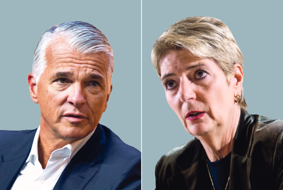 Zwei Personen im Porträt: Ein Mann mit grauem Haar im Blazer und eine Frau mit kurzen grauen Haaren vor grauem Hintergrund.