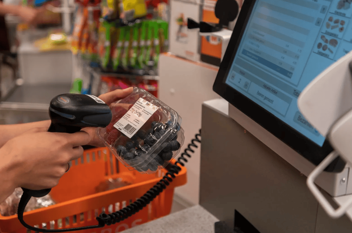 Personne scannant des baies avec un lecteur de codes-barres à une caisse en libre-service.