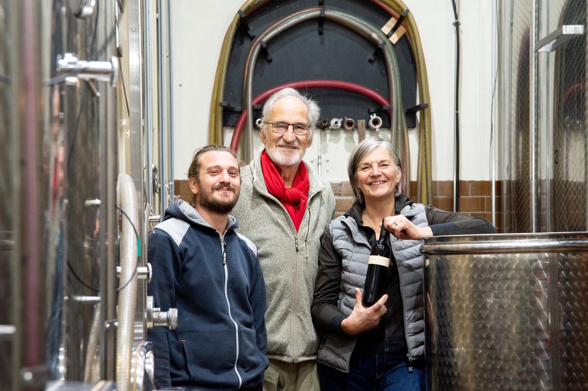Trois générations de la famille Hutins posent dans une cave à vin à Dardagny, avec Emilienne, Jean et Guillaume célébrant l'anniversaire de l'Esprit de Genève.