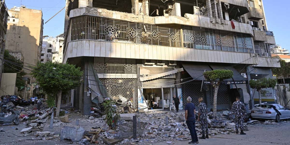 Ein Hezbollah-Anhänger hält ein Plakat mit Hassan Nasrallah vor den Trümmern eines zerstörten Gebäudes in Dahieh, Beirut.