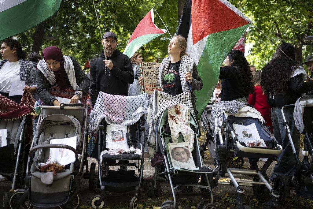 Manifestants à Bâle avec drapeaux palestiniens et pancartes lors d'un rassemblement, commémorant le conflit israélo-palestinien.