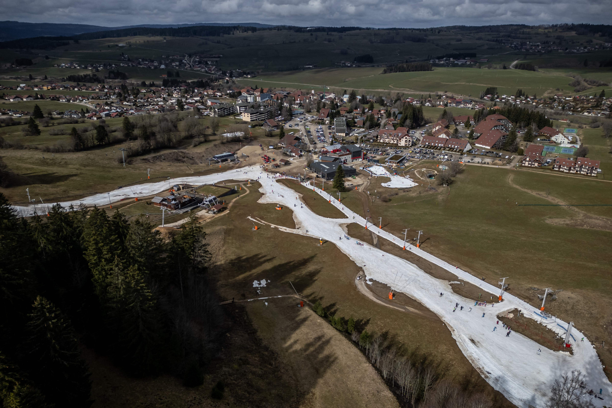 (FILES) An aerial photograph taken on February 20, 2024 shows ski slopes in a snowless landscape at the French Jura ski resort of Metabief. Faced with the challenge of climate change, the alpine ski resort of Metabief, the largest in the Jura mountains, has announced the closure of 30% of its ski area, sparking strong protests. (Photo by Fabrice COFFRINI / AFP)