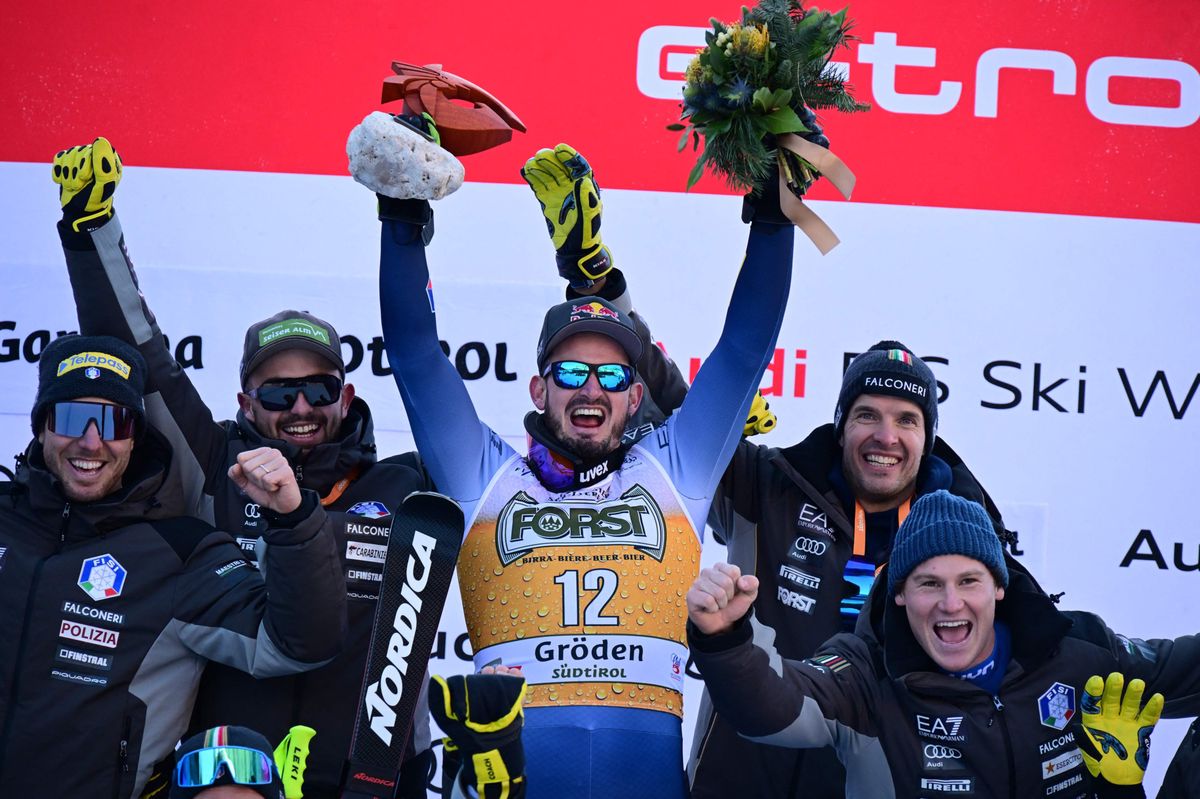 First placed Italian Dominik Paris poses with his team on the podium after winning the men's Downhill during the FIS Alpine Ski World Cup in Val Gardena on December 16, 2023. (Photo by Tiziana FABI / AFP)