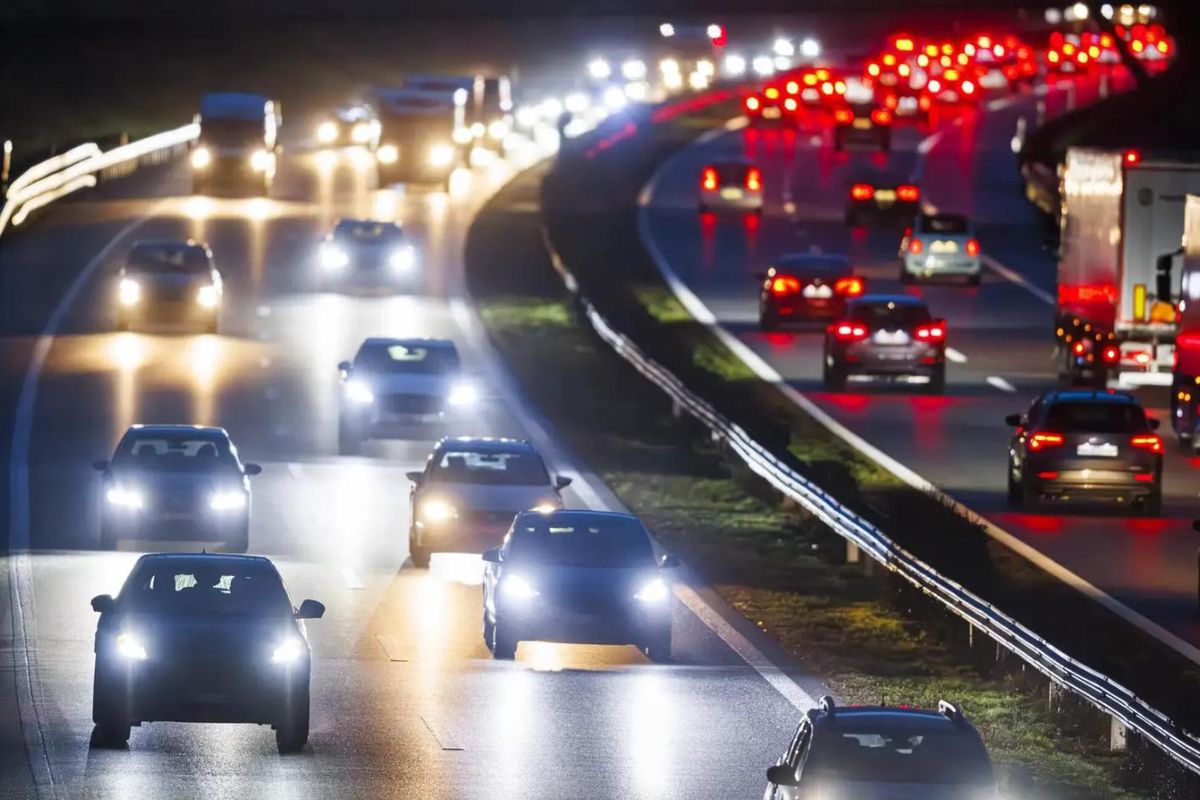 Trafic dense sur une autoroute éclairée la nuit, avec de nombreuses voitures circulant dans les deux sens.