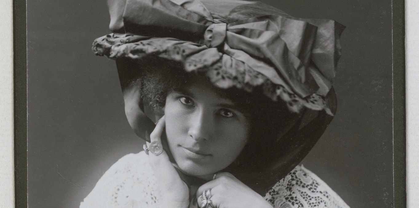 Photographie ancienne d'une femme, vêtue d'une robe à col en dentelle et un chapeau volumineux décoré d'un ruban. Signée en haut avec la mention manuscrite 'Guidée à Cuon 1907'.