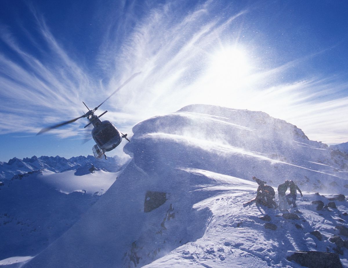 Canada B.C  Bella CoolaHeli Sk. Hélicoptère qui vole au-dessus des skieurs sur une montagne enneigée.