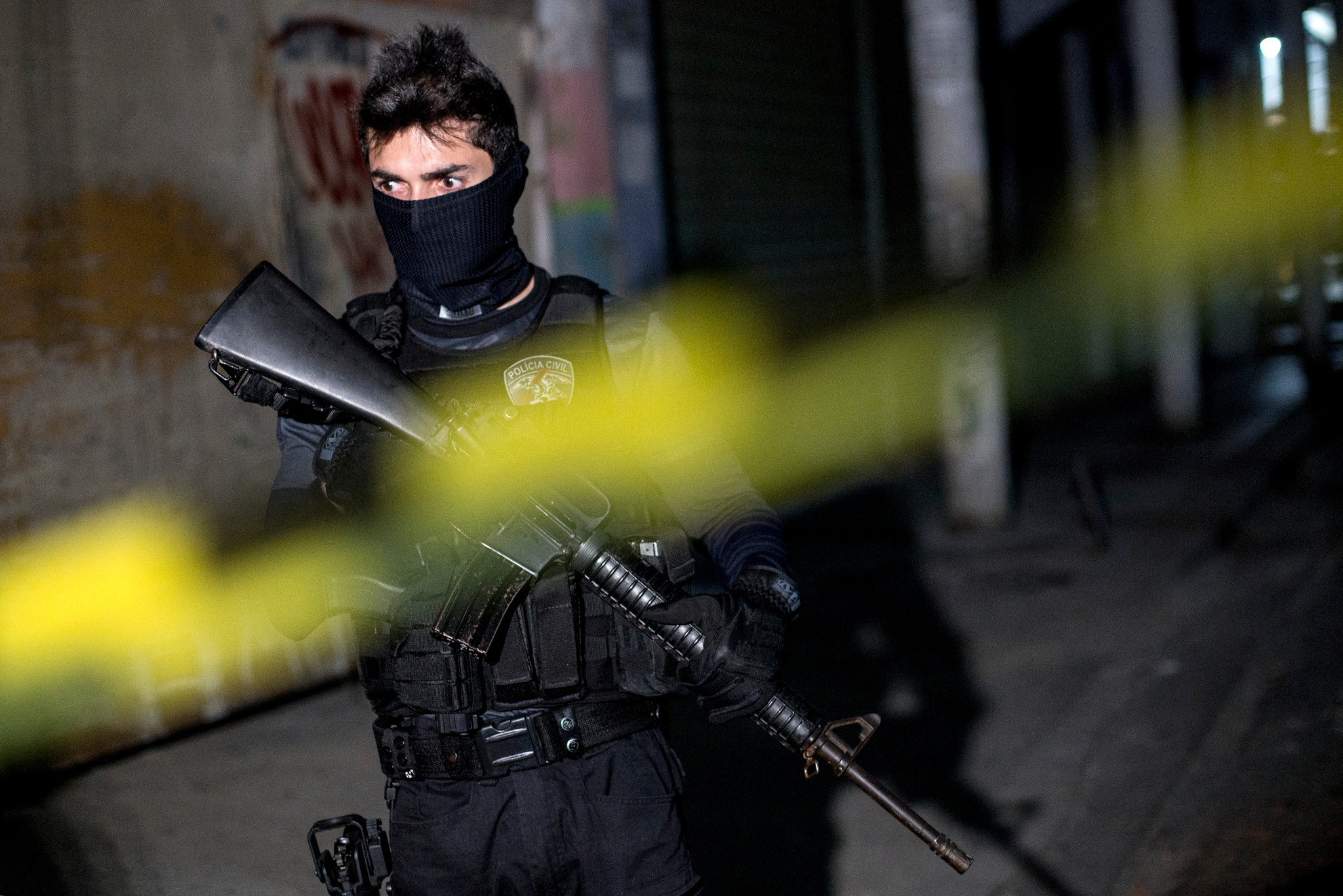 Un officier de police brésilien en tenue tactique avec un masque et un fusil d'assaut.