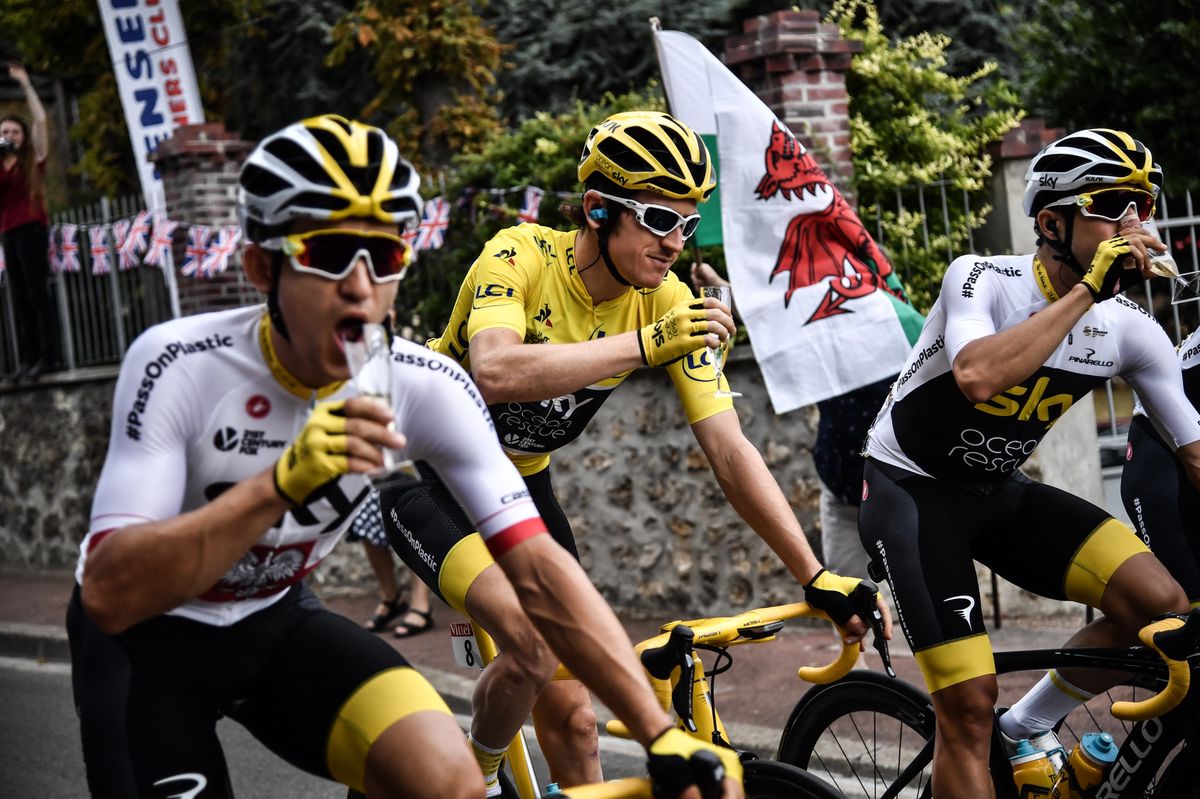 (L-R) Poland's Michal Kwiatkowski, Great Britain's Geraint Thomas (C) wearing the overall leader's yellow jersey and Spain's Jonathan Castroviejo  drink  champagne during the 21st and last stage of the 105th edition of the Tour de France cycling race between Houilles and Paris Champs-Elysees, on July 29, 2018. (Photo by Marco BERTORELLO / POOL / AFP)