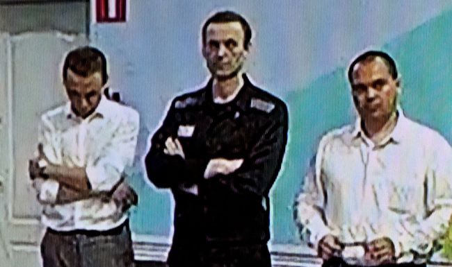 A screen shows the already imprisoned Russian opposition figure Alexei Navalny (2L) as he listens to his verdict over a series of extremism charges at the IK-6 penal colony, a maximum-security prison some 250 kilometres (155 miles) east of Moscow, in the settlement of Melekhovo in the Vladimir region on August 4, 2023. (Photo by Alexander NEMENOV / AFP)