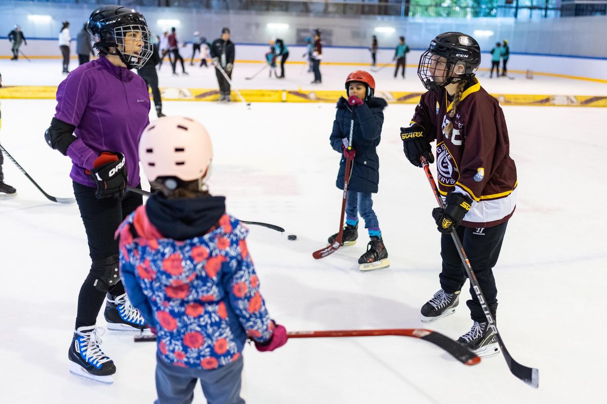 Des enfants en tenue de hockey sur glace discutent sur la patinoire lors de la journée d'initiation au hockey organisée par le Genève-Servette Hockey Club Féminin à Genève.
