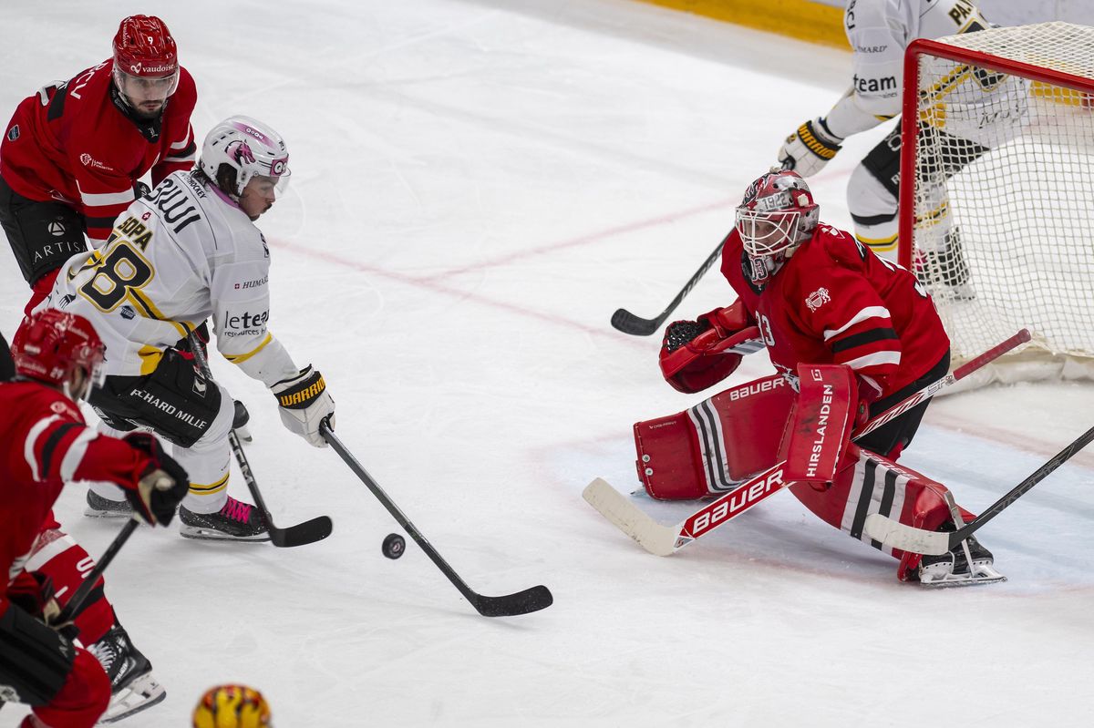 Damien Riat du LHC et Kyen Sopa du HCA s'affrontent pour le puck devant le gardien Kevin Pasche du LHC lors d'un match de hockey à la Vaudoise Arena, Lausanne.
