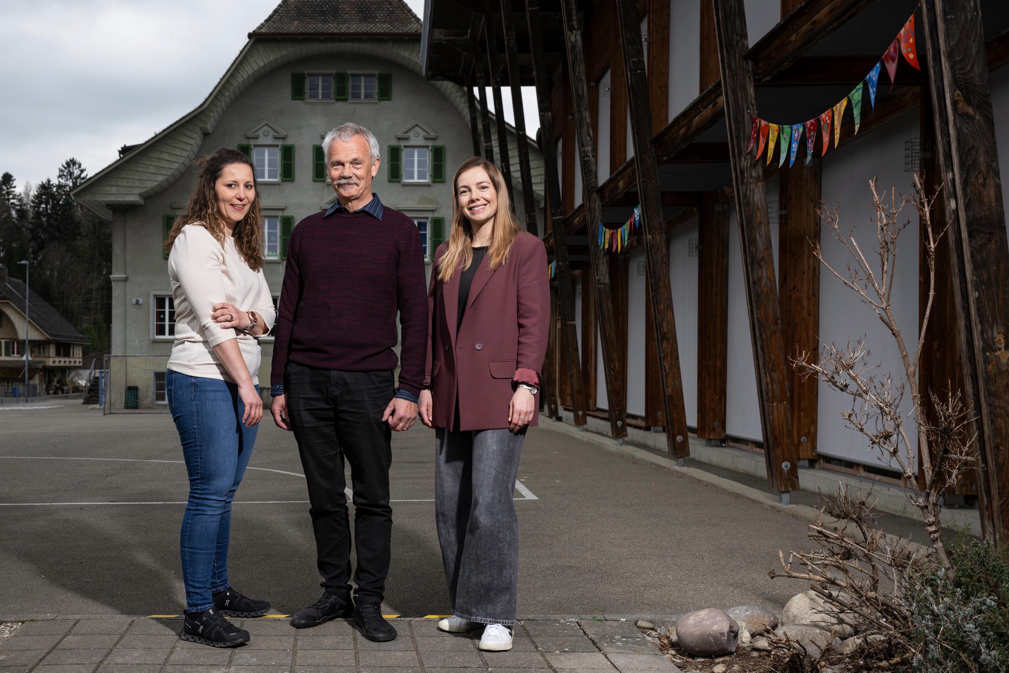Andrea Schüpbach, Martin Hunziker und Viktoria Murgovska posieren vor der Schule Trachselwald.