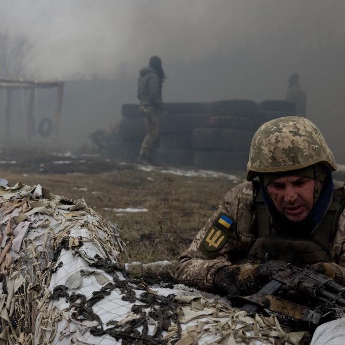 Un militaire ukrainien de la 24e Brigade mécanisée en position derrière des sacs de sable couverts de filet de camouflage, de la fumée s’élevant à proximité, lors d’un exercice d’entraînement dans l’est de l’Ukraine le 4 mars 2025.