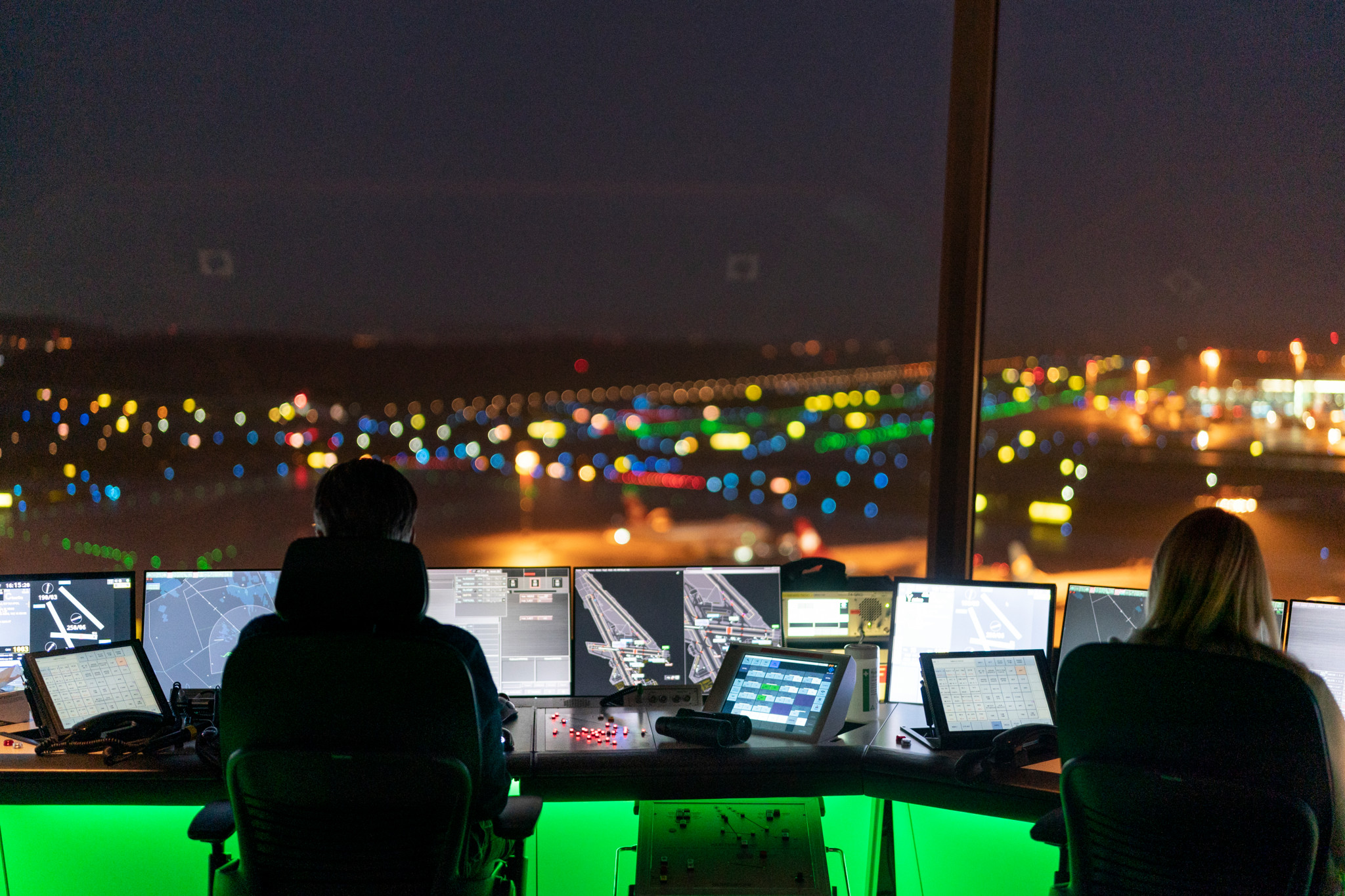 Mitarbeiter und Mitarbeiterin von Skyguide kontrollieren die Monitore und hat Blick auf das Flugfeld, bei Skyguide im Tower des Flughafen Zuerich Kloten, aufgenommen am Abend am Mittwoch, 23. November 2022. Im Tower am Flughafen Zuerich ueberwachen Flugverkehrsleiter der Skyguide die Starts und Landungen und den Flugverkehr in unmittelbarer Naehe des Flughafens Zuerich, in der Kontrollzone mit einem Radius von etwa 20 km um den Flughafen. (KEYSTONE/Gaetan Bally)