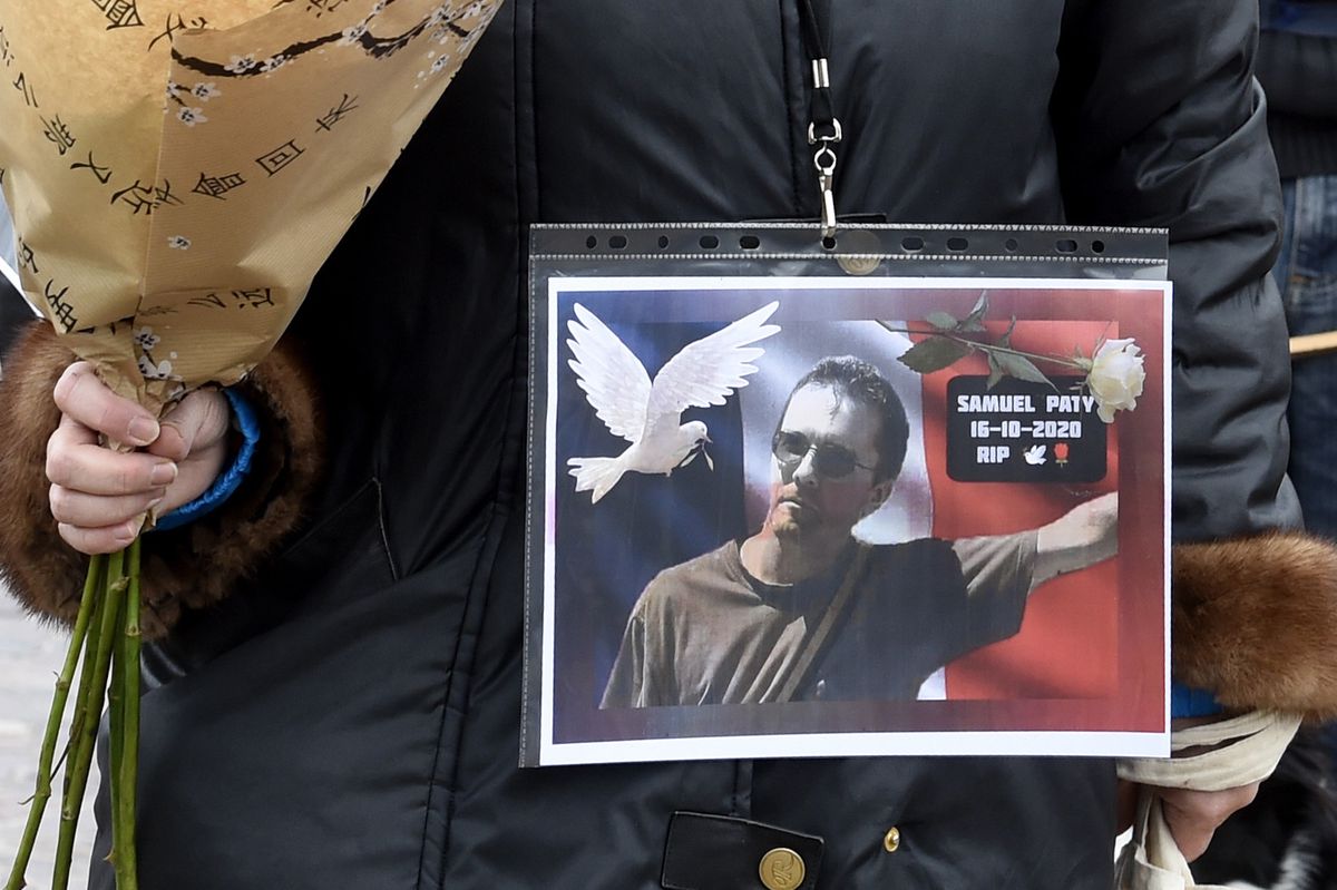 A woman holds a picture of Samuel Paty, Place de la Liberte in Lille on October 18, 2020, in homage to the history teacher, two days after he was beheaded by an attacker who was shot dead by policemen. - Thousands of people rally in Paris and other French cities on October 18 in a show of solidarity and defiance after a teacher was beheaded for showing pupils cartoons of the Prophet Mohammed. His murder in a Paris suburb on October 16 shocked the country and brought back memories of a wave of Islamist violence in 2015. (Photo by FRANCOIS LO PRESTI / AFP)