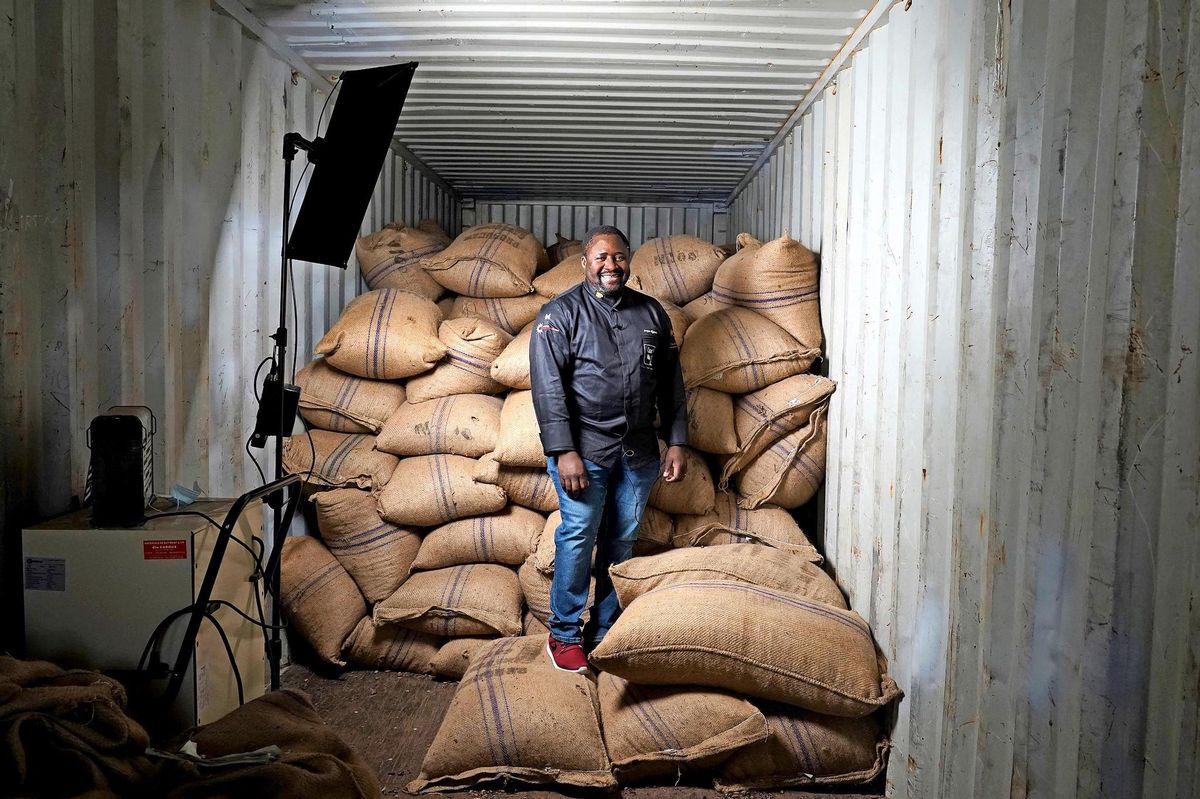 Serges Ngassa reçoit dans un conteneur de bateau posé à même le parking de sa boutique. À l’intérieur, les sacs de fèves de cacao arrivés directement de sa plantation. Photo: Lucien Fortunati