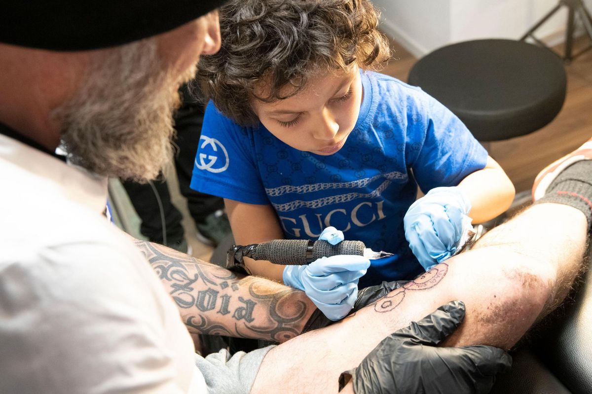 Dominique Fröhlich, tatoueur moudonnois propose des séances où ce sont les enfants qui tatouent leurs parents. Ici, le petit Marley tatoue son papa, Jean-Paul Gueirrero.