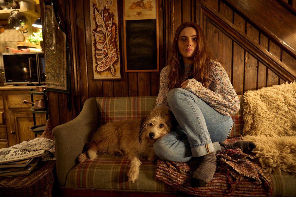 Une femme assise sur un canapé avec un chien dans un intérieur chaleureux en bois.