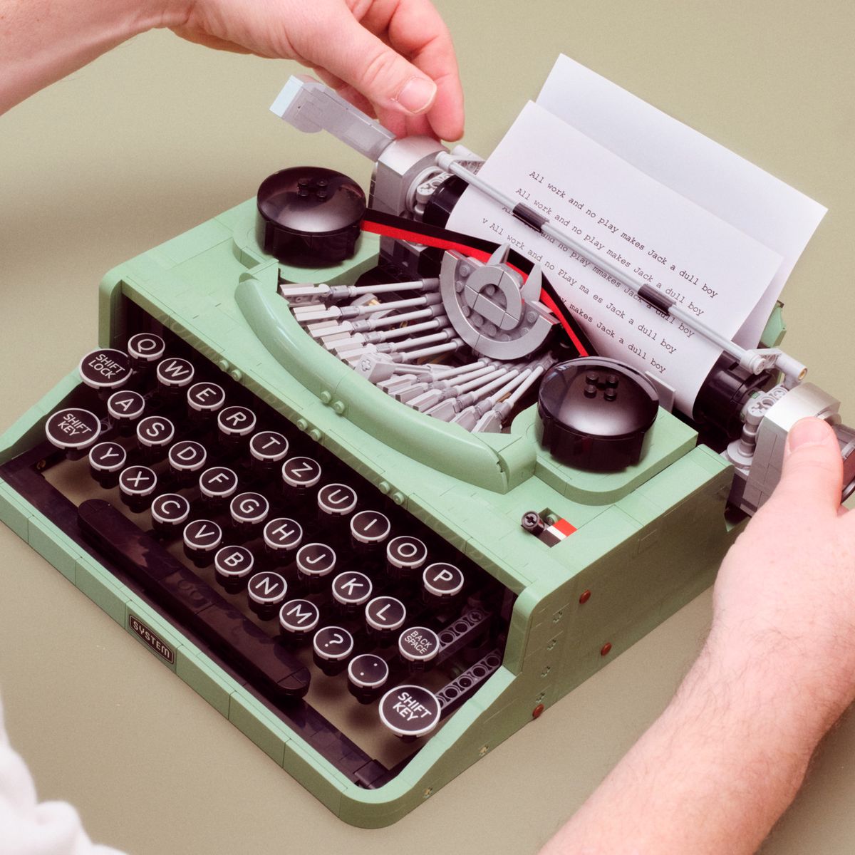 Person legt Papier in eine grüne Retro-Schreibmaschine ein.
